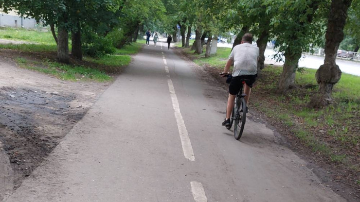 Велосипедист едет по пешеходной зоне. Навстречу слева идут мужчина и женщина по велодорожке.